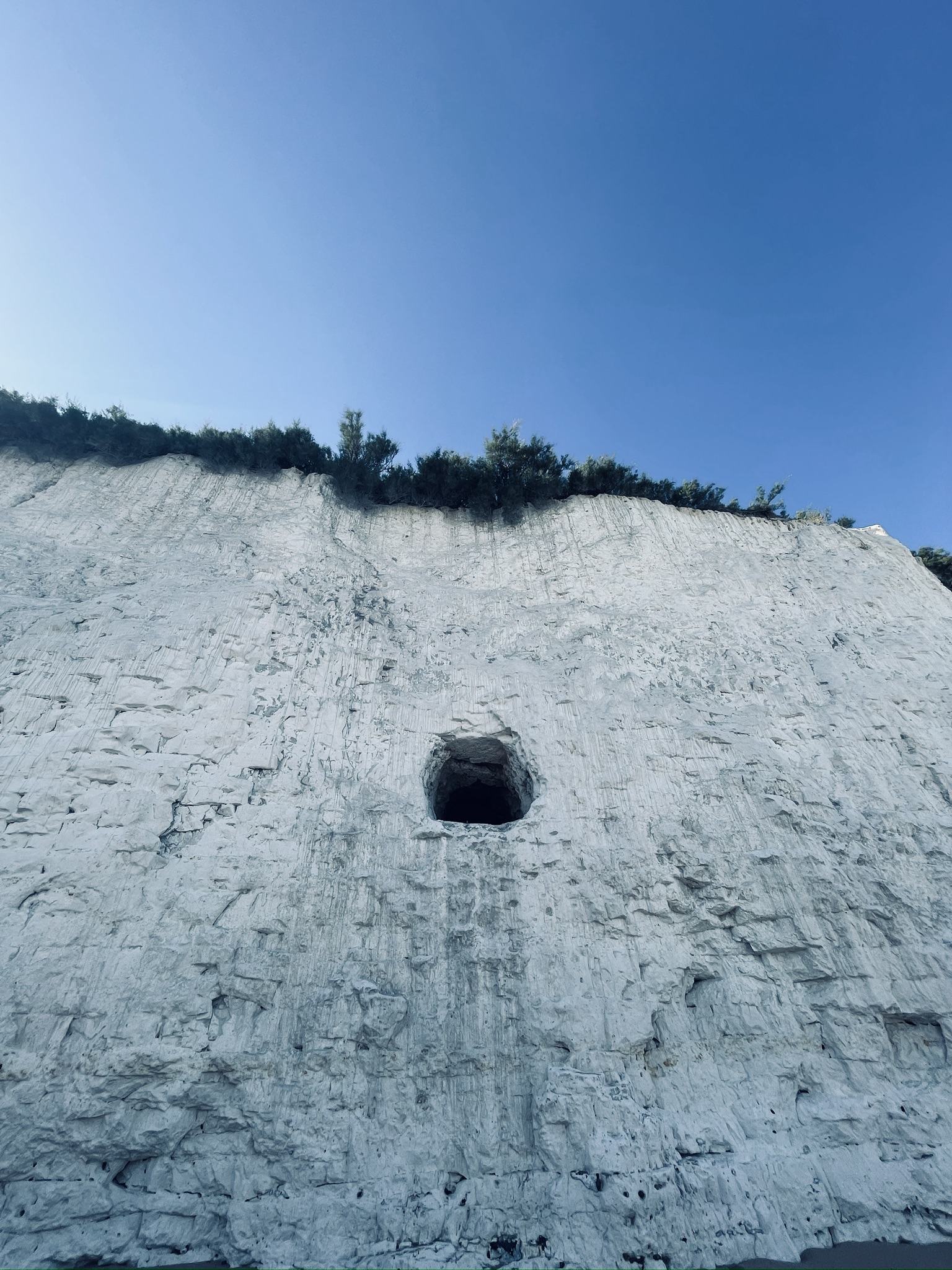 A pale chalk cliff under an open blue sky